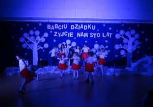 Żabki tańczą do piosenki "Chu chu ua" na na sali gimnastycznej w świetle kolorowych reflektorów.
